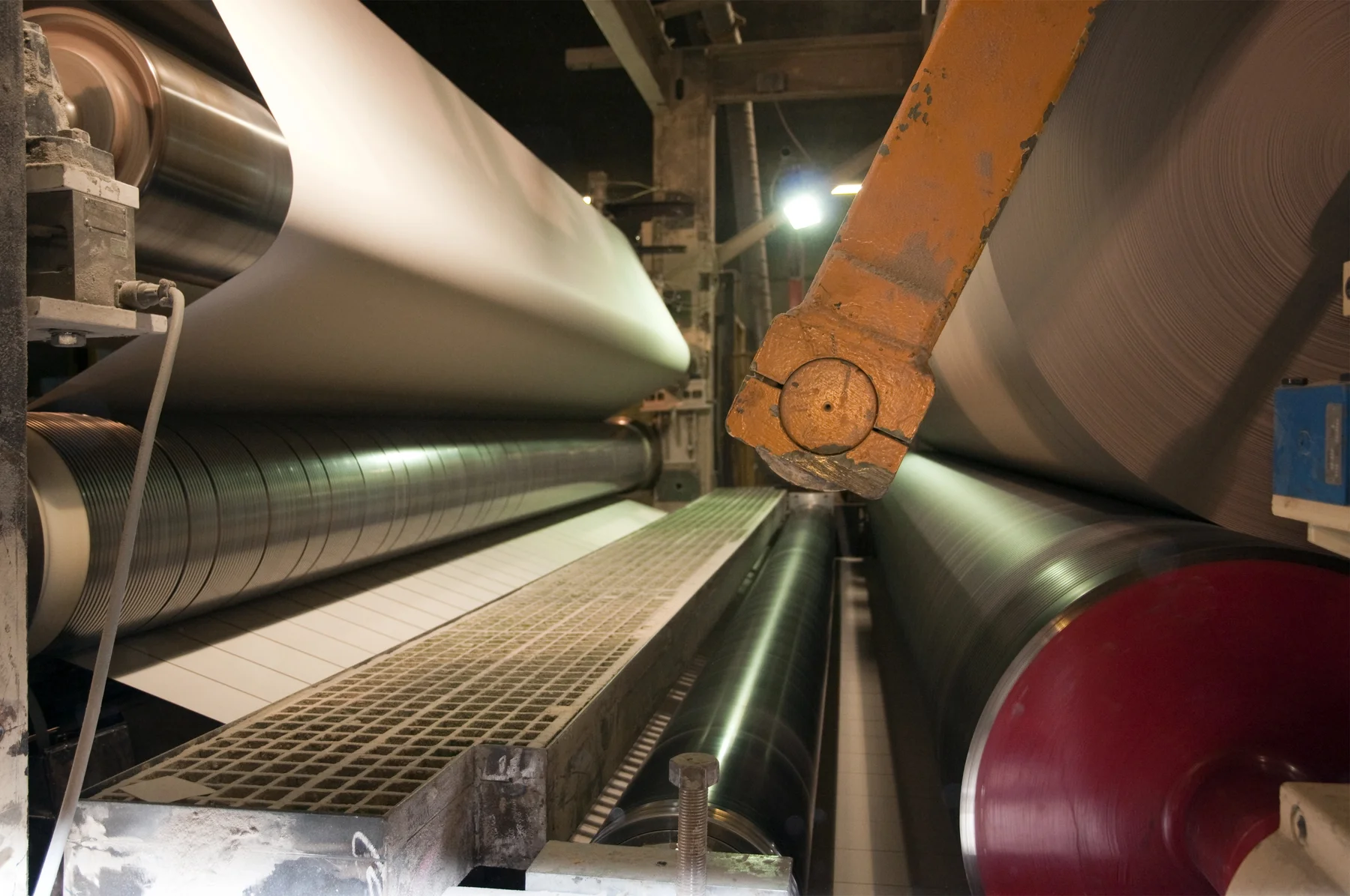 Walzen und laufende Papierbahn einer industriellen Papiermaschine